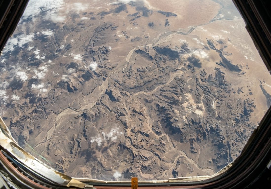 Vista da curvatura da Terra a partir da órbita baixa, com vastas formações de nuvens brancas sobre o azul profundo do oceano sob a luz solar direta.